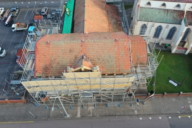 Aerial view of a large historic building undergoing roof restoration with extensive surrounding scaffolding.