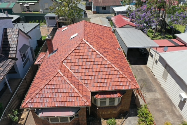 Aerial view of a house with a red-tiled roof surrounded by neighboring homes.